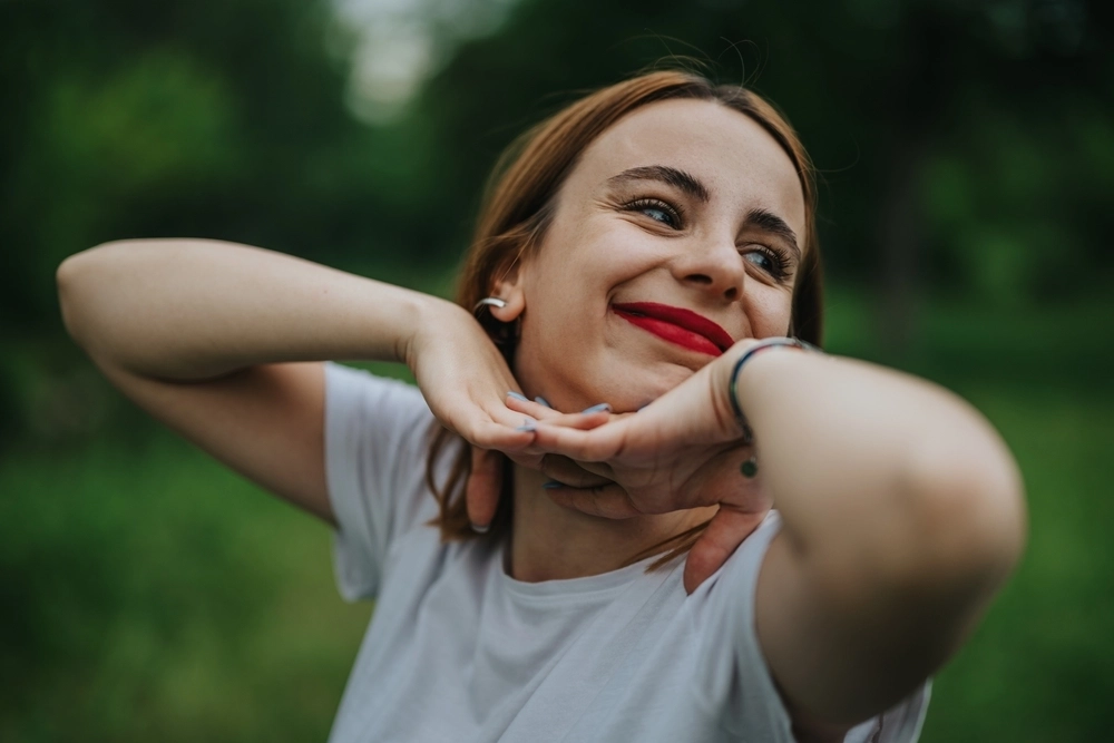 A smiling woman with light brown hair resting her chin on her hands