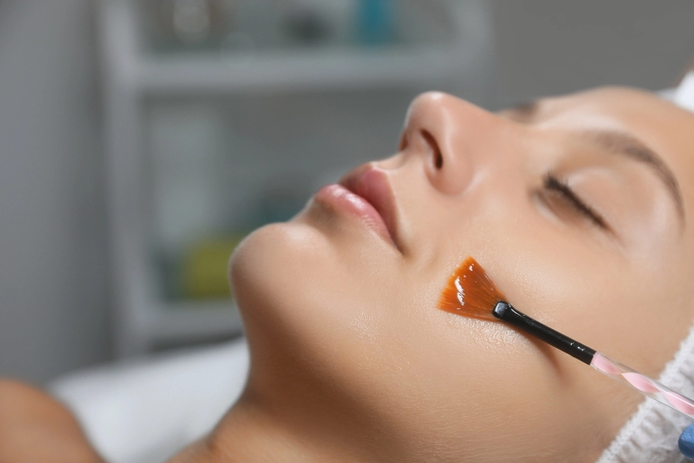 A brush applying an orange peel solution to a patient's cheek
