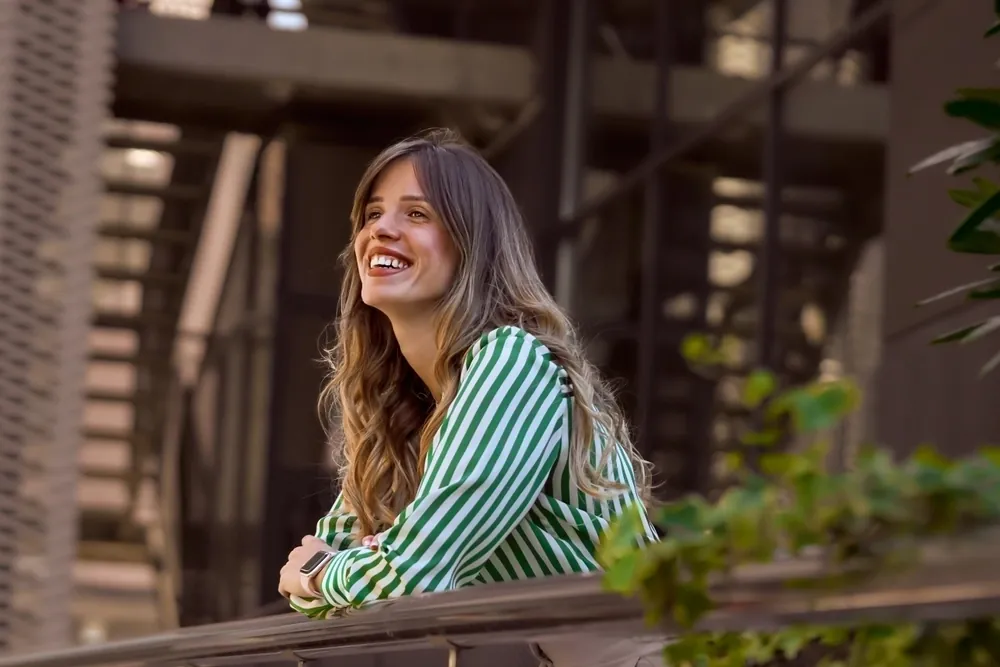 A woman in a striped shirt leaning on a railing outdoors
