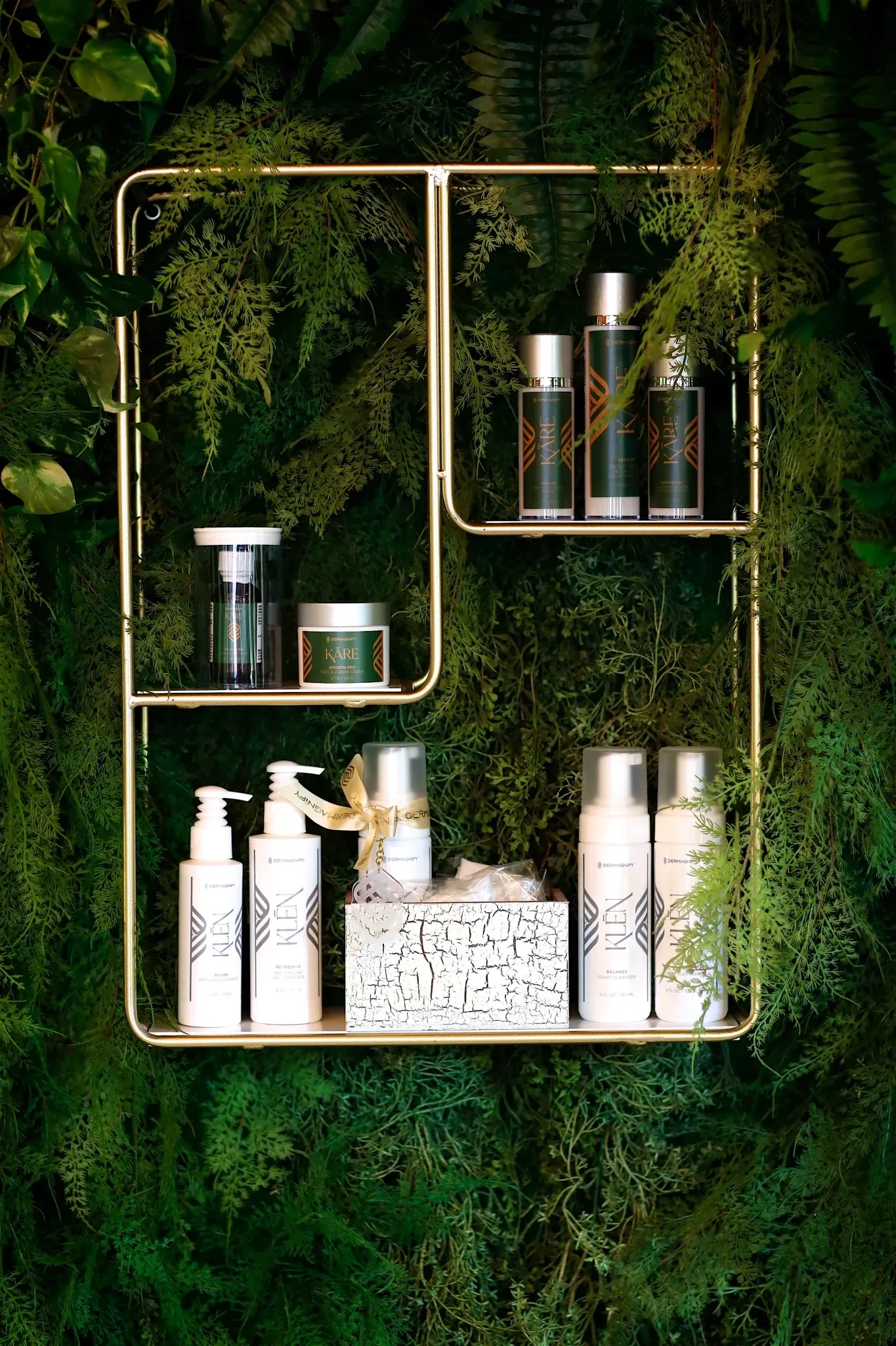 Skincare products arranged on gold shelves against foliage