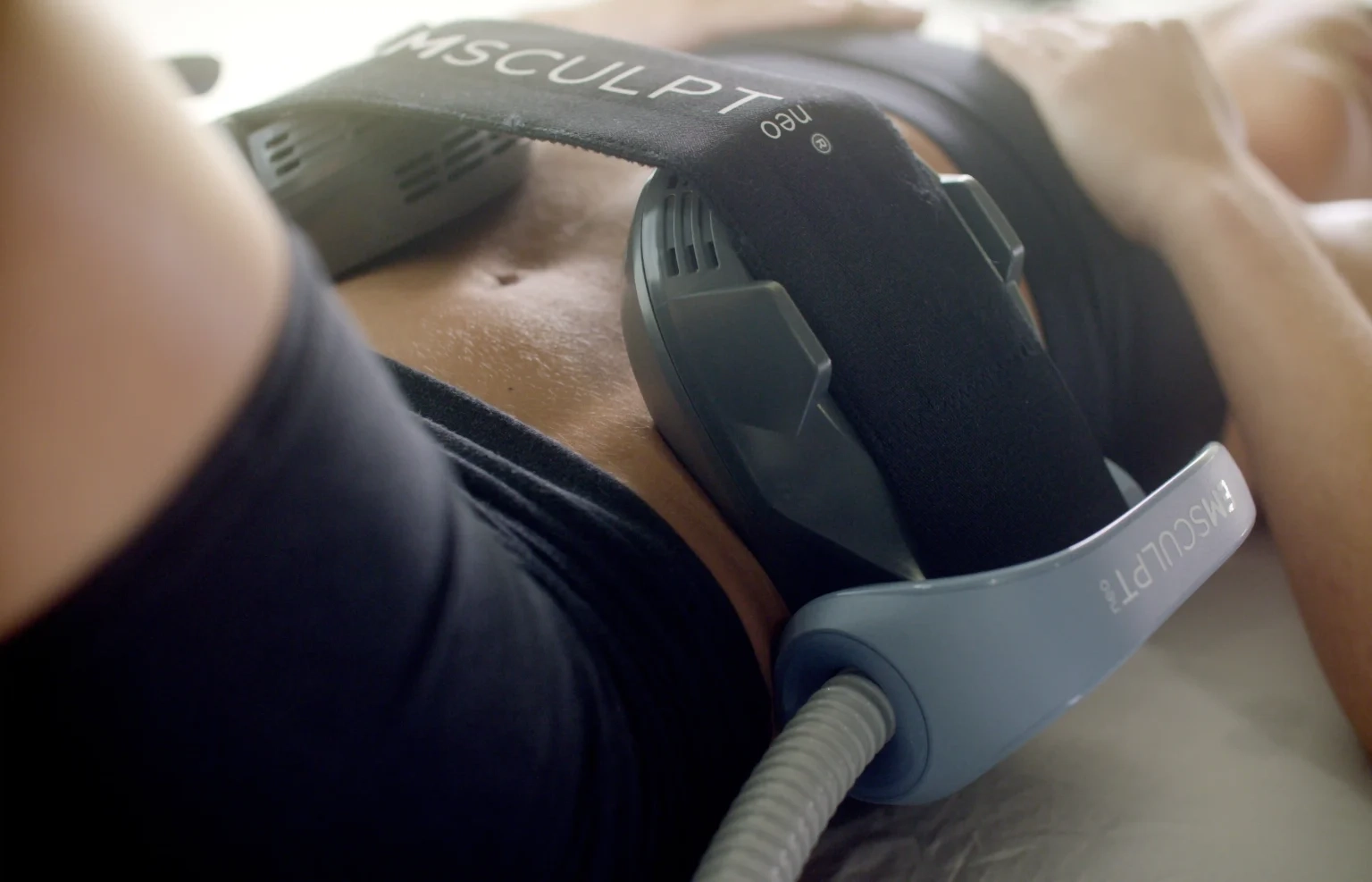 Emsculpt Neo applicator strapped across a patient's abdomen