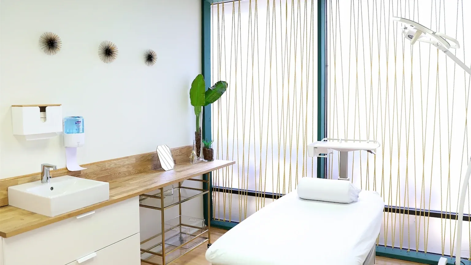 A Dermagnify treatment room with a treatment table, sink and natural light